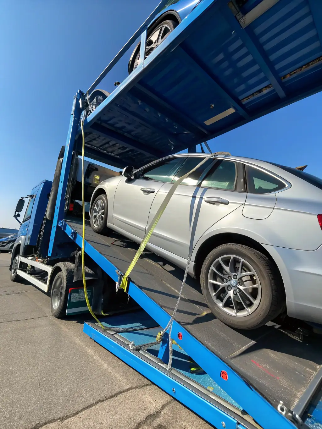 A car being carefully loaded onto a specialized car carrier inside a shipping container, ready for international transport.